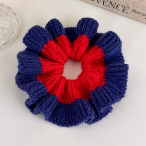 Close-up of dual-tone knit scrunchie featuring a red and dark blue woven wool texture