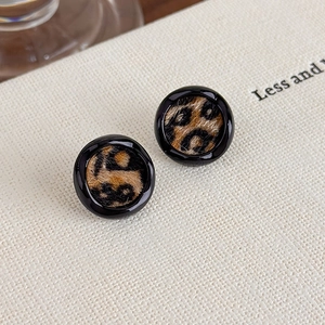 Gros plan de boucles d'oreilles léopard rondes avec bord noir sur fond texturé