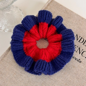 Close-up of contrast color knit hair scrunchie with soft ribbed texture and red-blue design