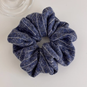 Detailed view of dark blue knitted scrunchie with white stripes and elastic texture