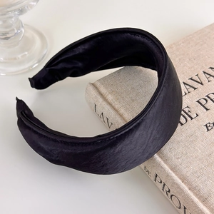 Close-up of high-quality black satin headband with thick sponge padded texture on a book