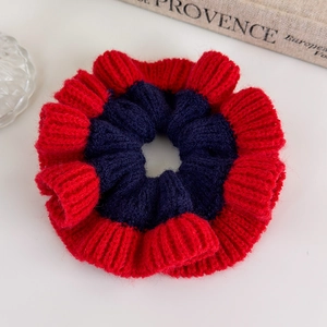 Detailed close-up of a two-tone knit scrunchie with red and navy blue woven texture