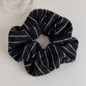 Detail of black knitted scrunchie with white stripes showing soft texture and cozy knit fabric