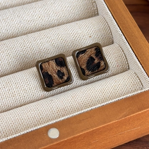 Gros plan de boucles d'oreilles carrées motif léopard avec texture fausse fourrure et bois