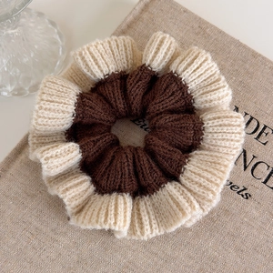 Close-up of dual-tone knit scrunchie showing detailed brown and cream wool textures