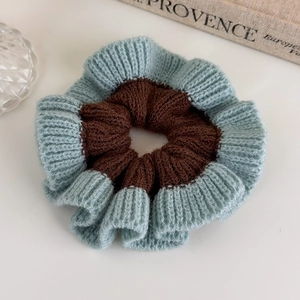 Detail of oversized knitted scrunchie with brown and mint green color-blocking texture