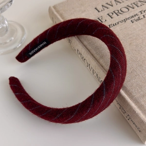 Detail of burgundy striped knit headband showing the handmade label and soft texture
