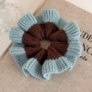 Detail of blue and brown handmade chunky knitted scrunchie showing soft yarn texture