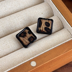 Détail de boucles d'oreilles carrées imprimé léopard dans un écrin en bois avec velours