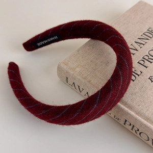 Detail of burgundy striped knit headband with handmade label on vintage book