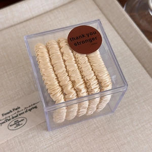 Vue détaillée de l'ensemble de chouchous en satin doré dans une boîte cadeau claire