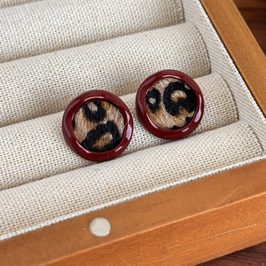Détail de boucles d'oreilles léopard avec émail bordeaux dans une boîte à bijoux en bois