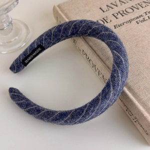 Detail of navy blue tweed headband featuring a black handmade label on woven fabric