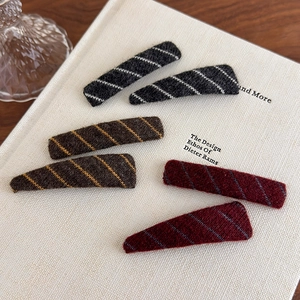 Detail of plush hair clips with diagonal knit stripes in black, tan and burgundy colors