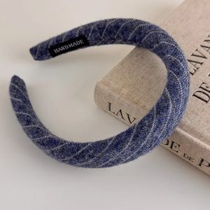 Close-up of handmade wide blue striped knit headband with soft tweed fabric texture