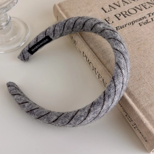 Detail view of handmade grey knitted striped headband resting on a vintage book