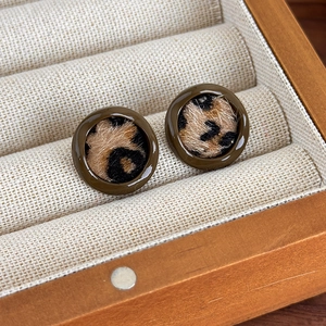 Gros plan de boucles d'oreilles rondes léopard avec cadre en résine sur support en lin
