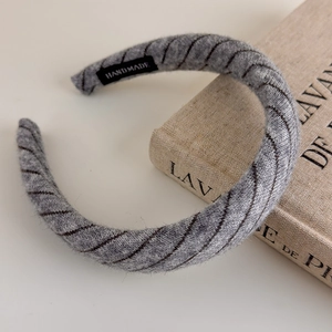 Detail of grey knitted striped headband with a handmade label on a decorative book