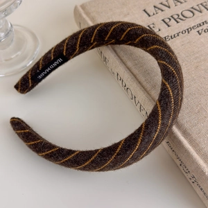 Detail of a brown fuzzy headband with yellow stitching and a handmade woven label
