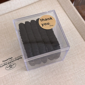 Détails de chouchous en satin noir plissé dans une boîte cadeau en acrylique clair