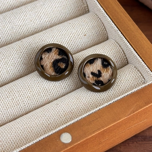 Détail de boucles d'oreilles rondes léopard avec texture fausse fourrure et bord résine