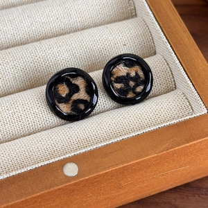 Gros plan sur les boucles d'oreilles rondes léopard avec texture velours dans un écrin