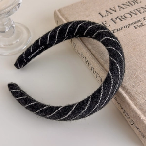 Detail showing handmade label on a thick striped knitted headband over a vintage book