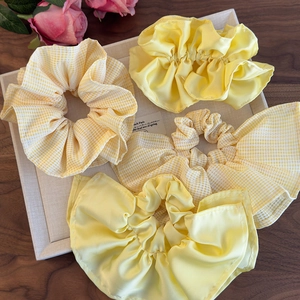 Lot de 4 chouchous jaunes en satin et à carreaux sur un plateau avec fleurs