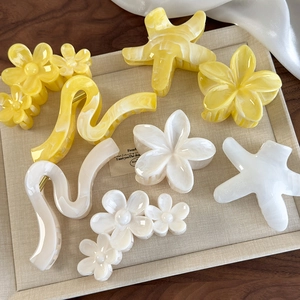 Elegant yellow and white starfish flower hair claws set on beige fabric for vacation