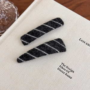 Close-up of black and white striped plush hair clips on a white minimalist background