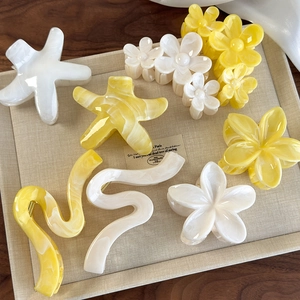 Close-up of yellow starfish and flower hair claws in marble acetate finish