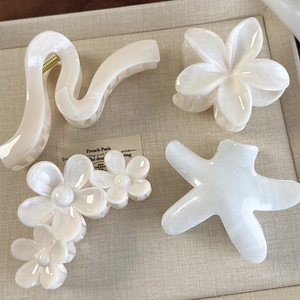 Detail view of cream acetate hair claws featuring floral and starfish shapes in retro style