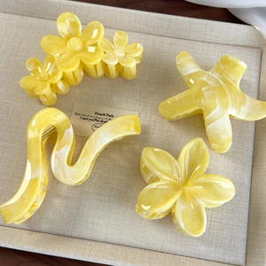 Detailed shot of yellow marble textured hair claw clips featuring flower and starfish designs
