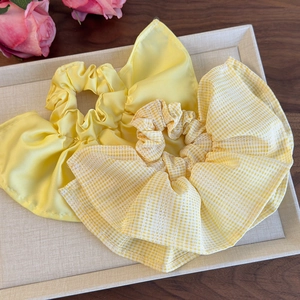 Détail de chouchous plissés en satin jaune et à carreaux sur un plateau beige