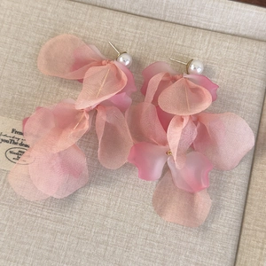 Macro shot of pink gradient fabric flower petals with white pearls on earrings