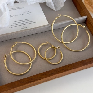 Three pairs of gold hoop earrings in small, medium, and large sizes with a matte shimmer finish