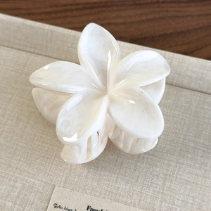 Detail view of cream white plumeria hair claw clip with elegant marble texture finish