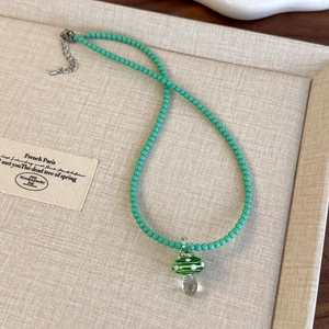 Dettaglio della collana di perline verde menta con ciondolo a fungo e chiusura in metallo