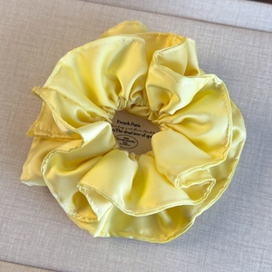 Gros plan détaillé sur un chouchou en satin jaune crème avec des plis doux et soyeux