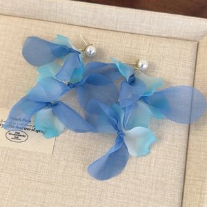 Detail of blue gradient chiffon flower earrings with pearls on a textured display tray