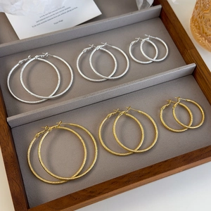 Detail view of gold and silver glitter textured hoop earrings in three sizes on a tray