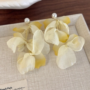 Detail of elegant yellow gradient fabric flower earrings with pearls and gold metal links