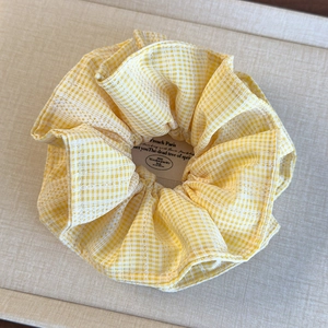 Vue détaillée du chouchou à carreaux jaunes avec une bordure en dentelle blanche