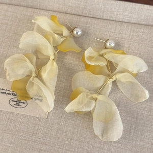 Macro shot of layered organza flower petals with white pearl bead on elegant earrings