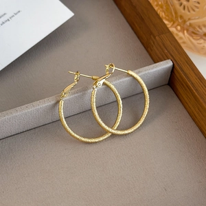 Detailed macro view of gold-finished hoop earrings with a textured frosted surface