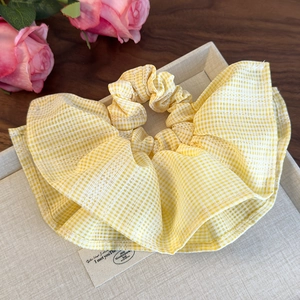 Détail du chouchou vichy jaune avec bordure en dentelle blanche sur plateau