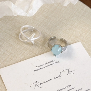 Detailed shot of starfish cross ring and light blue gemstone ring on artistic backdrop