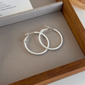 Macro detail of silver frosted hoop earrings with shimmering glitter finish and metal texture