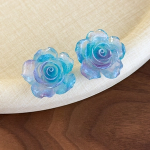 Détail macro de boucles d'oreilles rose avec dégradé bleu-violet et paillettes