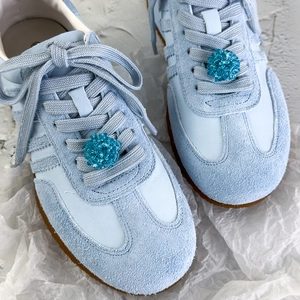 Détail de breloques en perles de cristal et nœud en tulle bleu sur baskets en daim